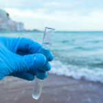 Analysis of a sample of water from a river or sea, ocean. The scientist in the glove took water in a test tube.